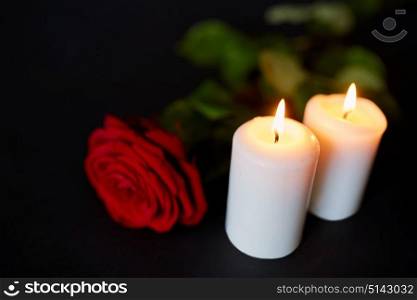 funeral and mourning concept - red rose and burning candles over black background. red rose and burning candles over black background