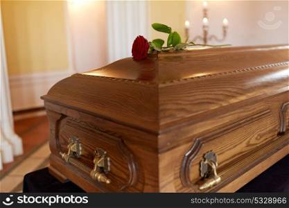 funeral and mourning concept - red rose flower on wooden coffin in church. red rose flower on wooden coffin in church
