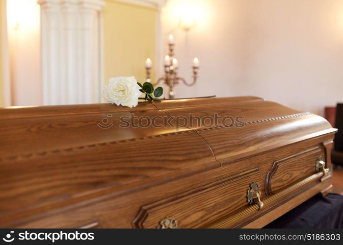 funeral and mourning concept - white rose flower on wooden coffin at funeral in church. rose flower on wooden coffin at funeral in church
