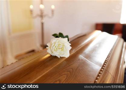 funeral and mourning concept - white rose flower on wooden coffin in church. white rose flower on wooden coffin in church