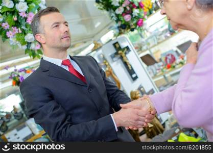 Funeral director shaking hands with elderly woman