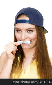 Funky people concept. Young woman with chewing gum. Bubble gum is in the silver paper. Girl is wearing cap and yellow shirt.. Young woman with chewing gum.