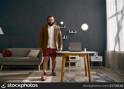 Funny bearded man in jacket and red shorts. Freelancer online distance work at home office. Full-length freelance businessman in jacket and shorts