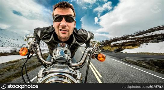 Funny Biker in sunglasses and leather jacket racing on mountain serpentine.
