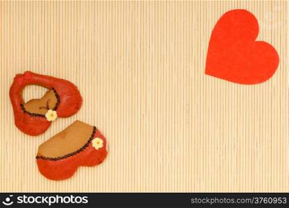Funny bikini underwear shape gingerbread cake cookie sweet dessert with icing and decoration and red heart love symbol valentine&#39;s day border or frame on beige bamboo mat background