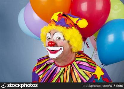 Funny birthday clown with a bunch of helium balloons.