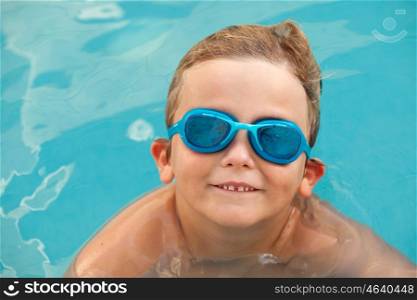 Funny blond boy with swimming goggles in the pool