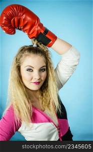 Funny blonde girl female boxer in big fun red gloves playing sports boxing studio shot on blue. Funny girl in red gloves playing sports boxing