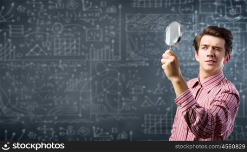 Funny botanist. Young man scientist looking in magnifying glass