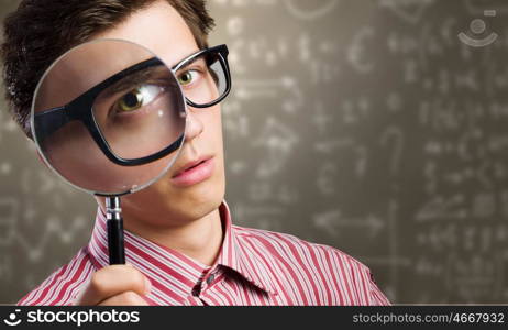 Funny botanist. Young man scientist looking in magnifying glass