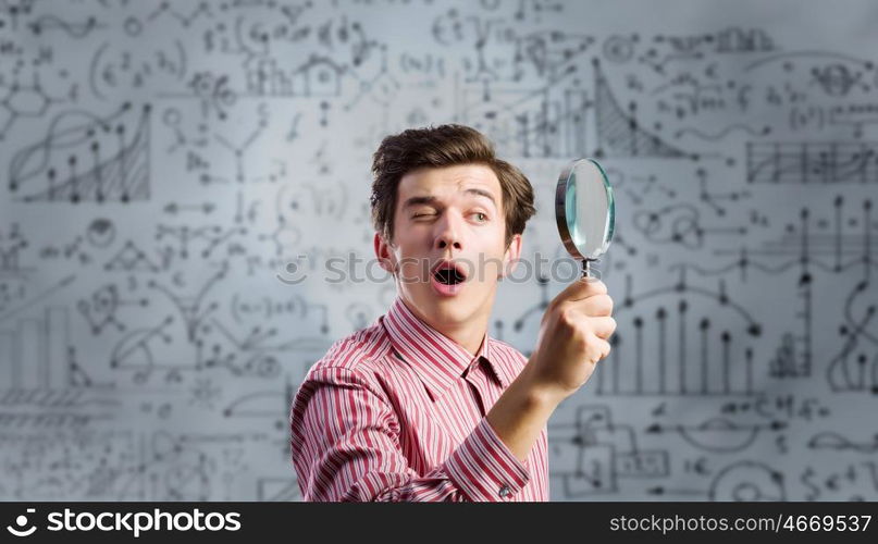 Funny botanist. Young man scientist looking in magnifying glass