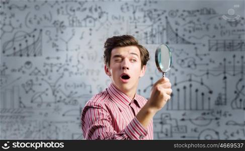 Funny botanist. Young man scientist looking in magnifying glass