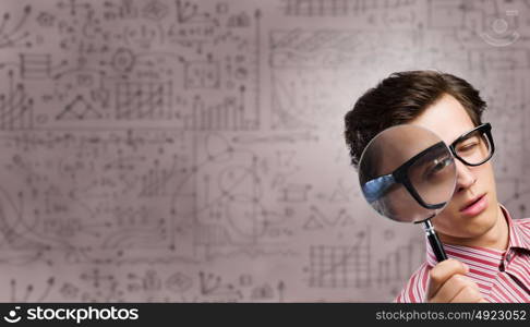 Funny botanist. Young man scientist looking in magnifying glass