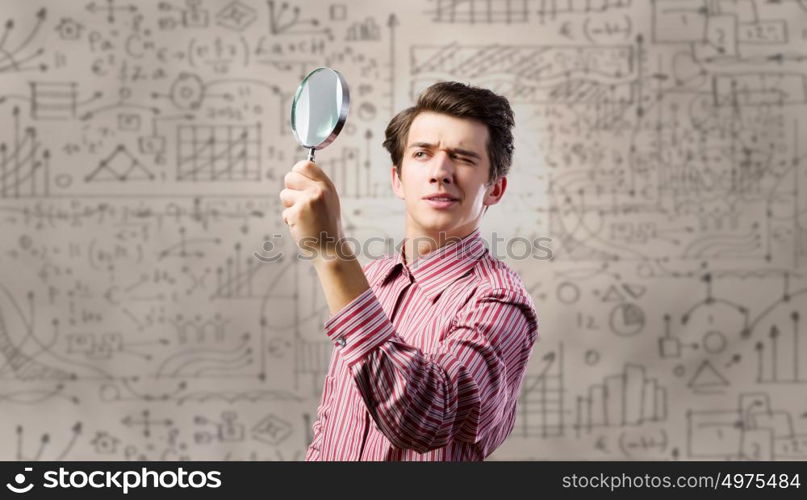 Funny botanist. Young man scientist looking in magnifying glass