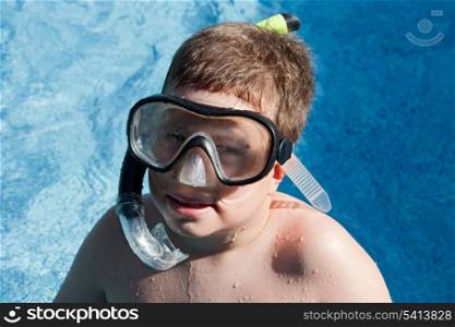 Funny boy with diving goggles and snorkel swimming in the water
