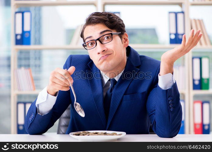 Funny businessman eating gold coins in office