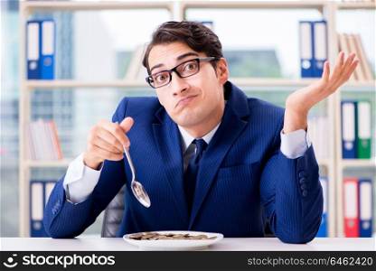 Funny businessman eating gold coins in office