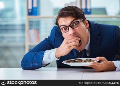Funny businessman eating gold coins in office