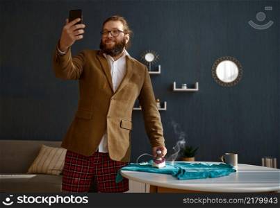Funny businessman having phone business video chat meeting ironing clothes. Work from home. Businessman having phone video chat ironing clothes
