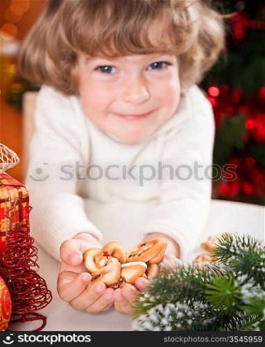 Funny child holding cookies against Christmas lights background