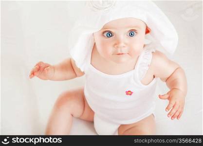 funny child on white fabric in white hat