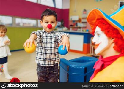Funny clown animator and group of little boys. Birthday celebrating in playroom, baby holiday in playground. Childhood happiness, childish leisure, entertainment in children&rsquo;s area. Funny clown animator and group of little boys