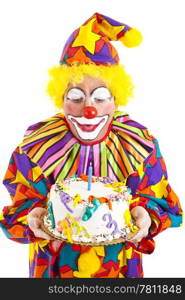 Funny clown blows out a candle on the birthday cake. Isolated on white.