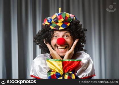 Funny clown in humorous concept against curtain