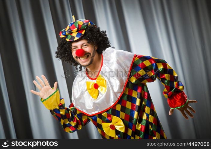 Funny clown in humorous concept against curtain