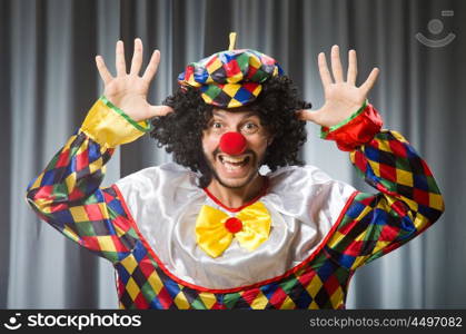 Funny clown in humorous concept against curtain