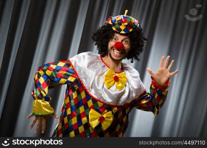 Funny clown in humorous concept against curtain