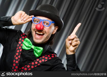 Funny clown in humorous concept against curtain