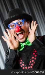 Funny clown in humorous concept against curtain