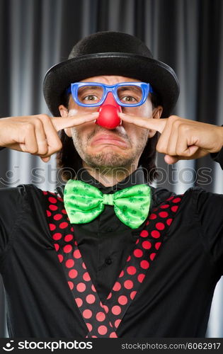 Funny clown in humorous concept against curtain