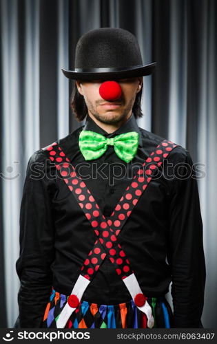 Funny clown in humorous concept against curtain