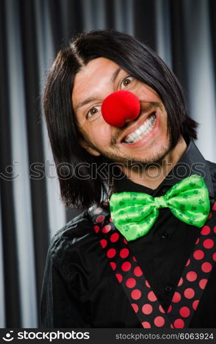 Funny clown in humorous concept against curtain