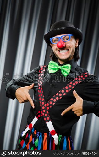 Funny clown in humorous concept against curtain