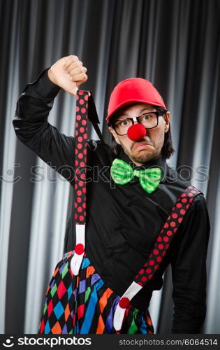 Funny clown in humorous concept against curtain