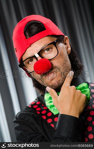 Funny clown in humorous concept against curtain