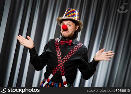 Funny clown in humorous concept against curtain