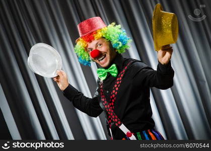 Funny clown in humorous concept against curtain