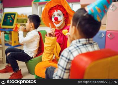 Funny clown play with cheerful children together. Birthday party celebrating in playroom, baby holiday in playground. Childhood happiness, childish leisure. Funny clown play with cheerful children together