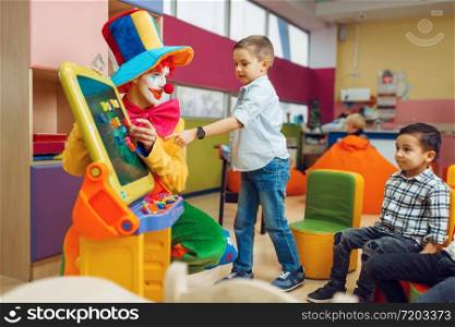 Funny clown with joyful children play in the alphabet on board. Birthday party celebrating in playroom, baby holiday in playground. Childhood happiness, childish leisure. Clown with joyful children play in the alphabet