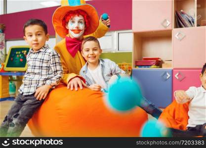 Funny clown with little boy in kindergarten. Birthday celebrating in playroom, baby holiday in playground. Childhood happiness, childish leisure. Funny clown with little boy in kindergarten
