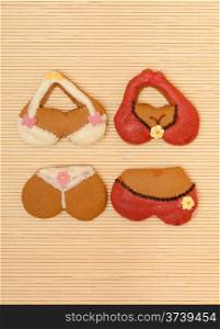 Funny colorfull bikini shape gingerbread cakes cookies sweet dessert with icing and decoration on beige bamboo mat