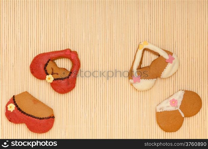 Funny colorfull bikini shape gingerbread cakes cookies sweet dessert with icing and decoration border or frame on beige bamboo mat