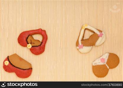 Funny colorfull bikini shape gingerbread cakes cookies sweet dessert with icing and decoration border or frame on beige bamboo mat