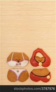 Funny colorfull bikini shape gingerbread cakes cookies sweet dessert with icing and decoration border or frame on beige bamboo mat background