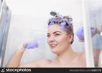 Funny crazy woman having coloring shampoo on her hair, purple washing product. Toning blonde color at home concept.. Funny woman with toner shampoo on her hair
