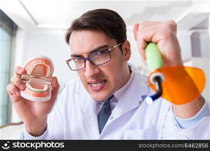 Funny dentist with curing light in medical concept